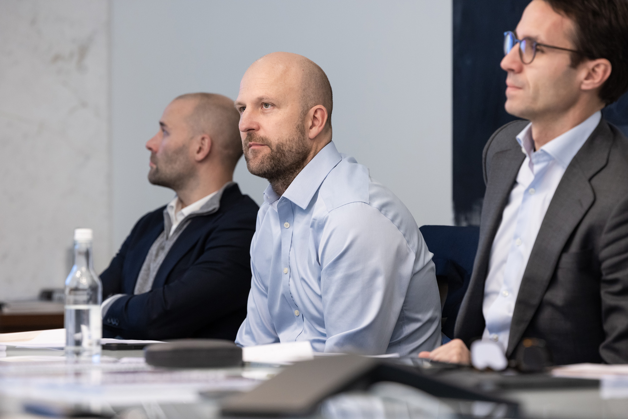 3 men sitting at a conference table attentive to the meeting