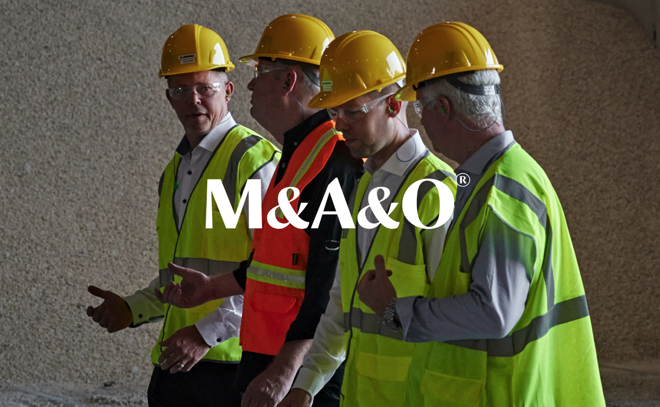 a group of 4 builders walking with hard hats and reflective vests with the text M & A & O placed on top of the image