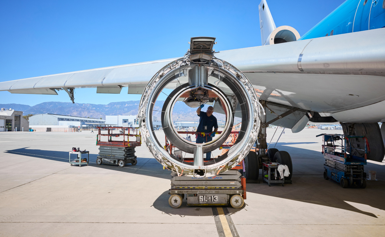 image of airplane engine from the side with a person standing behind it